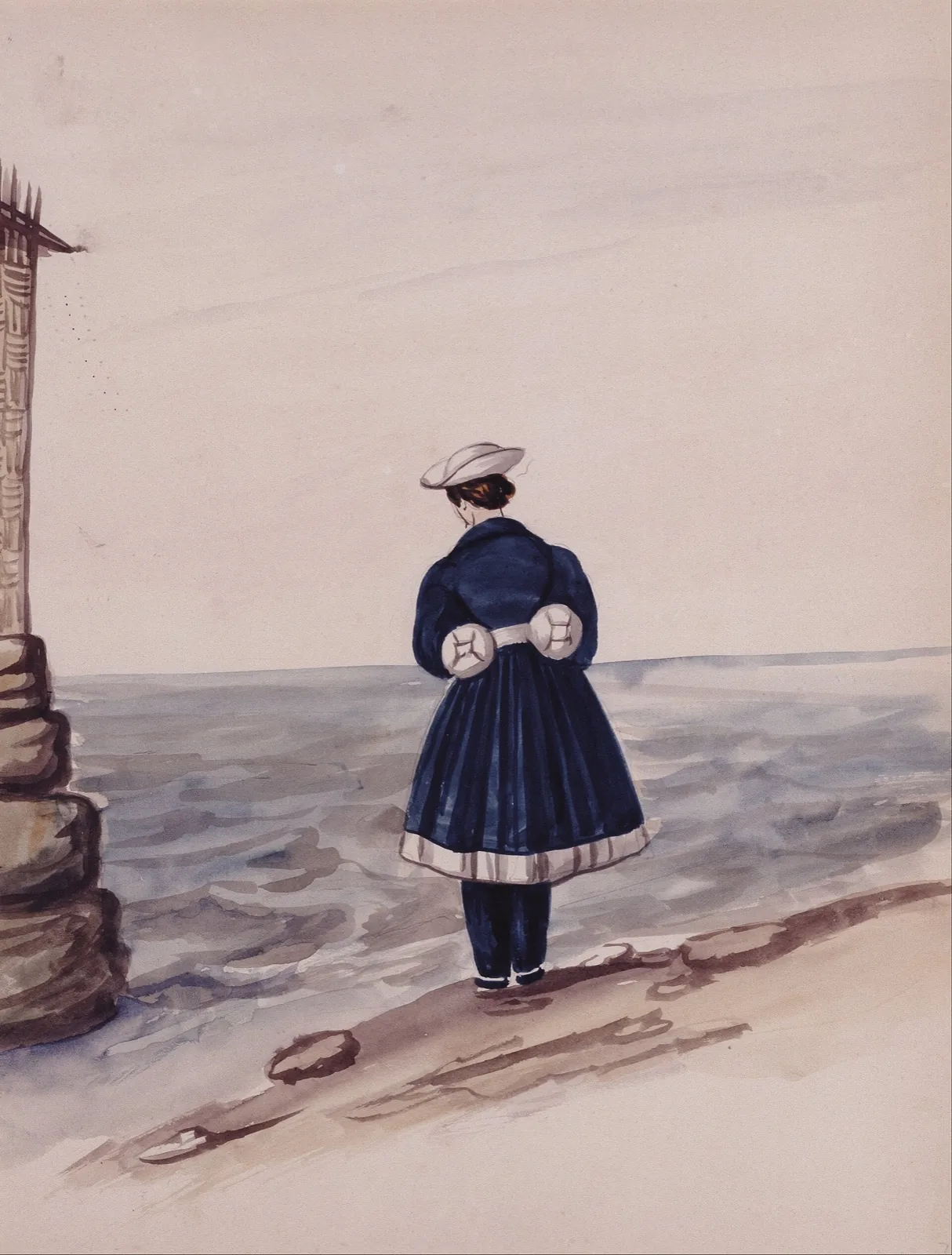 Woman seen from behind in a navy coat and white hat, standing at the water's edge facing a gray sea