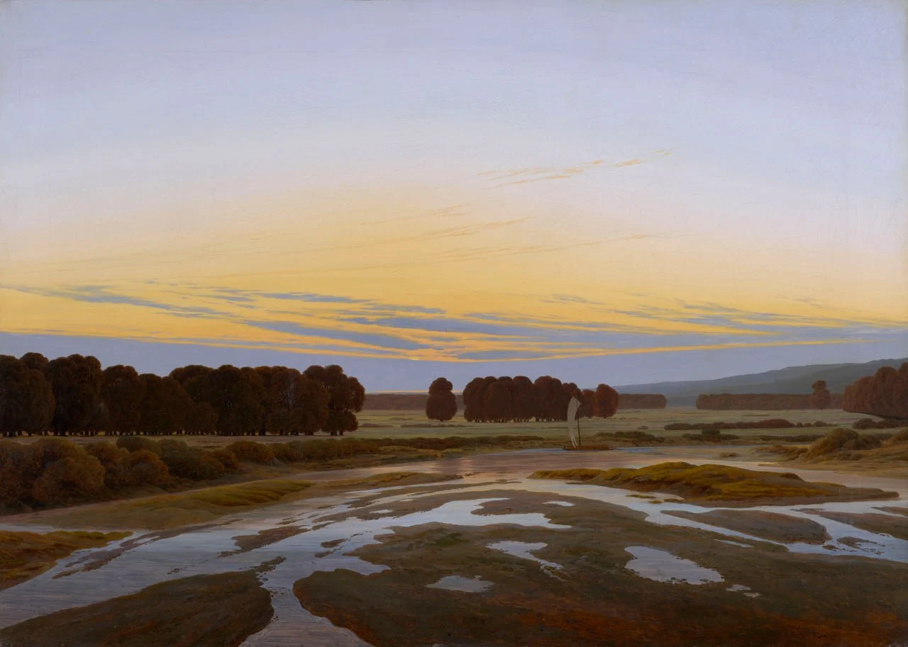 Llanura inundada con charcos que reflejan un cielo amarillo de atardecer, con grupos de árboles oscuros al fondo