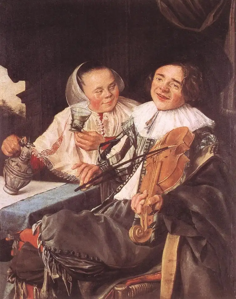A woman in a white cap holds a glass and a jug beside a smiling young man playing a violin, at a table