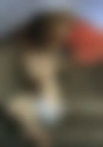 Mujer desnuda sentada en un banco de piedra se aparta y alza las manos ante dos hombres que se asoman por un muro
