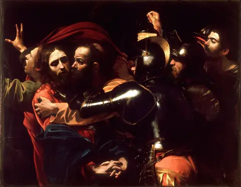 Jesús, con las manos entrelazadas, rodeado de soldados con armaduras negras y brillantes mientras un hombre lo besa