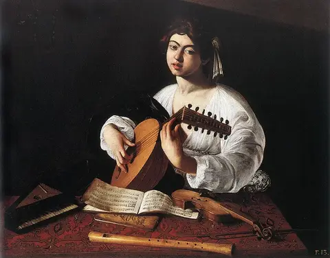 Joven de camisa blanca toca un laúd tras una mesa con libros de música, un violín, una flauta y un pequeño teclado