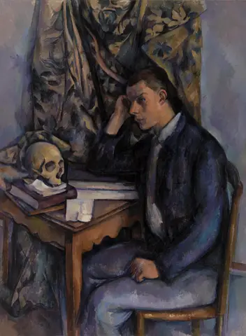 Joven de saco azul sentado a una mesa, con la cabeza apoyada en la mano, junto a una calavera sobre libros