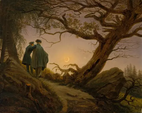 Two men seen from behind, one resting a hand on the other’s shoulder, gaze at a crescent moon beside a twisted oak
