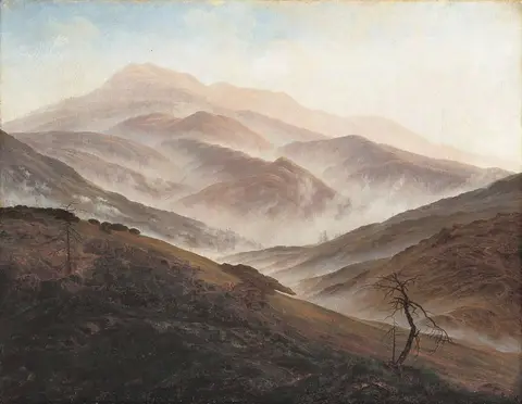 Cadenas de montañas una tras otra entre niebla, con una ladera oscura y un árbol seco en primer plano