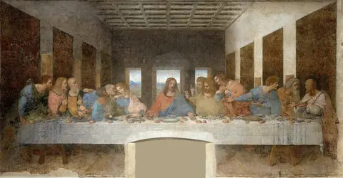 Jesús sentado al centro de una mesa larga con mantel blanco, entre doce apóstoles agitados, frente a tres ventanas