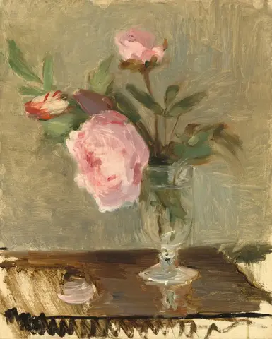 Peonías rosas en una copa de vidrio sobre una mesa café, con pétalos caídos y un fondo verde grisáceo