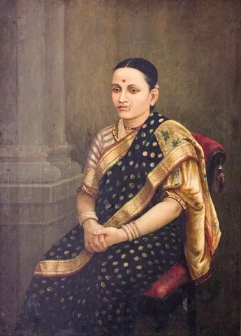 Mujer sentada en un sillón rojo, con sari negro de lunares dorados, chal dorado y manos juntas, junto a una columna