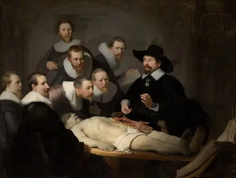 Médico de sombrero negro muestra el brazo de un cadáver a siete hombres de cuello blanco que se inclinan a mirar