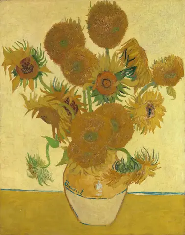 Ramo de girasoles amarillos y anaranjados, unos abiertos y otros marchitos, en un jarrón sobre una mesa amarilla