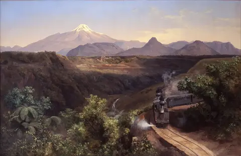 Tren de vapor sale de una curva entre vegetación tropical, junto a una barranca profunda, con un volcán nevado al fondo
