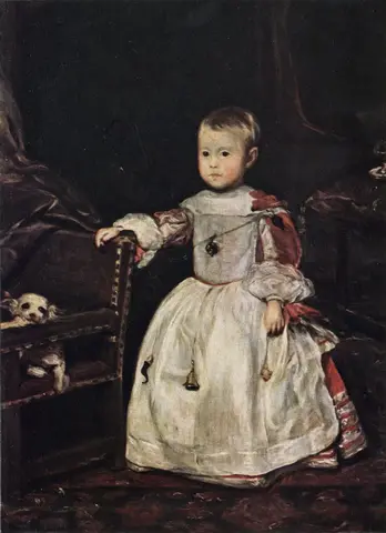 Niño pequeño de pie con delantal blanco sobre vestido rojo apoya la mano en una silla donde se asoma un perrito