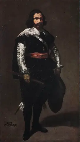 Bearded man in black with silver sleeves and a red sash, standing with a short baton in one hand and a hat in the other