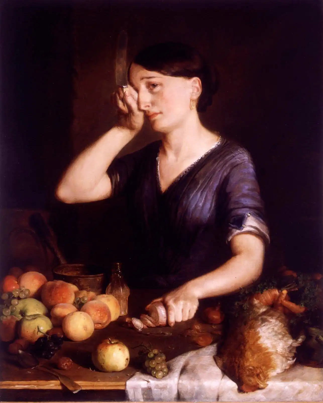 Woman in a purple dress rubbing one eye with the hand that holds a knife as she peels an onion, beside fruit
