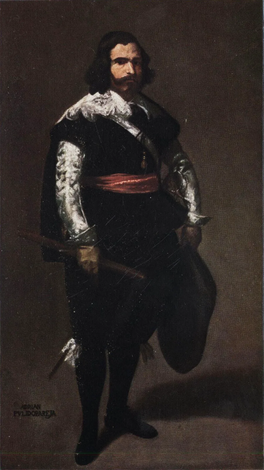 Hombre barbado de negro, con mangas plateadas y faja roja, de pie con un bastón en una mano y un sombrero en la otra