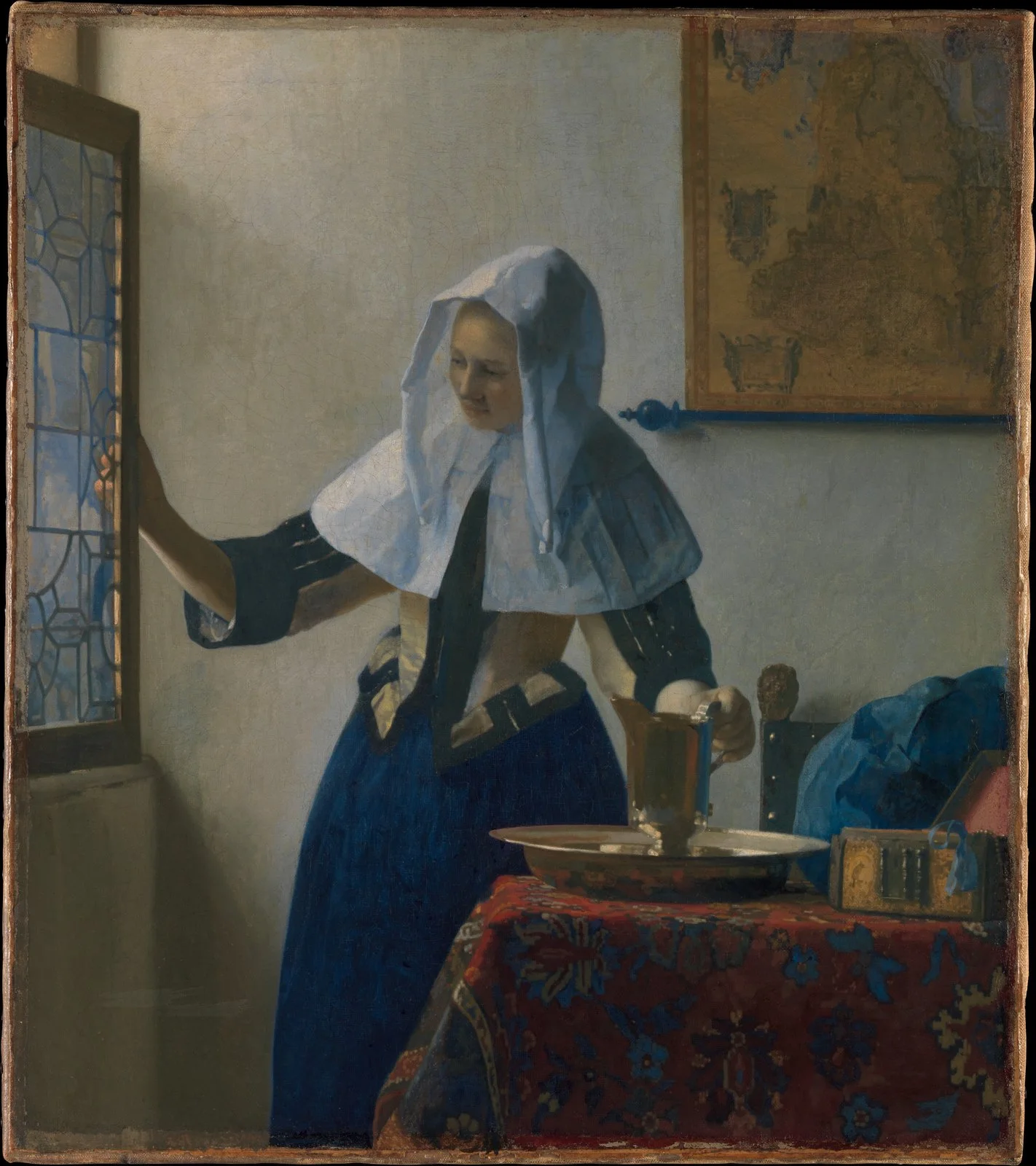 Woman in a white head covering opens a window with one hand and holds a metal pitcher in a basin with the other
